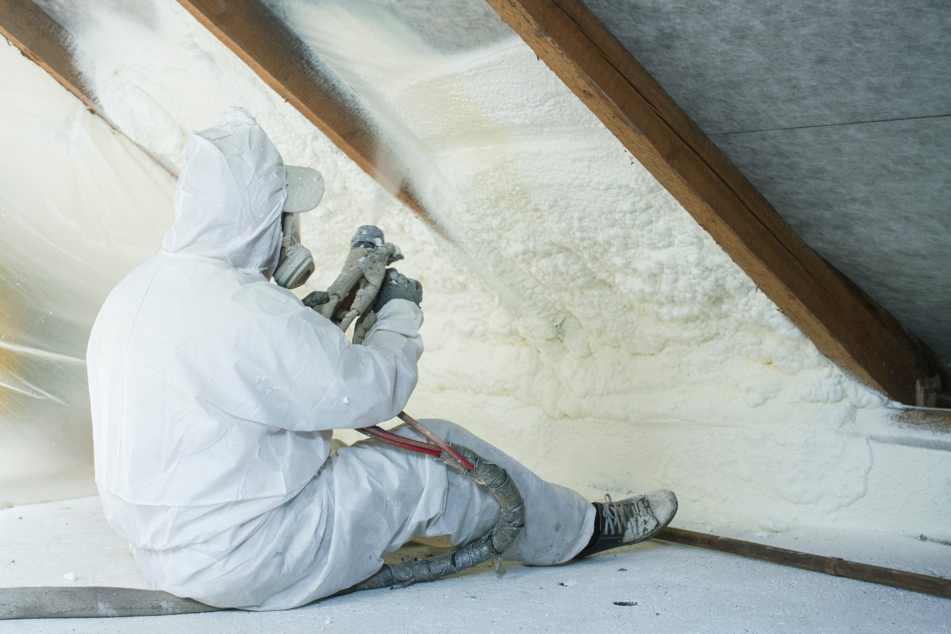 Technician spraying spray foam insulation on roof