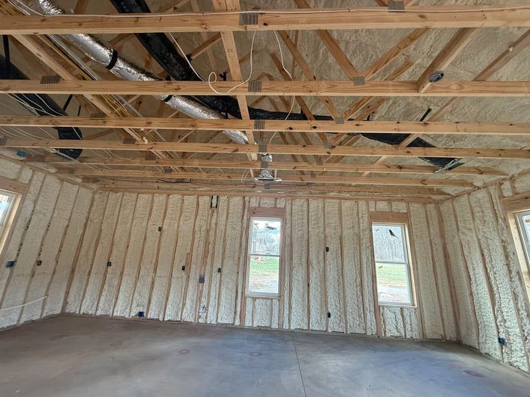 Interior of unfinished garage with exposed wooden framing, drywall, and concrete floor under construction