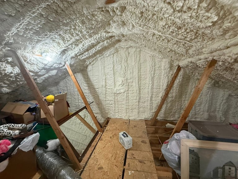 Basement or storage room with wooden chair frames, plastic sheeting on walls and ceiling, and various boxes and items scattered around