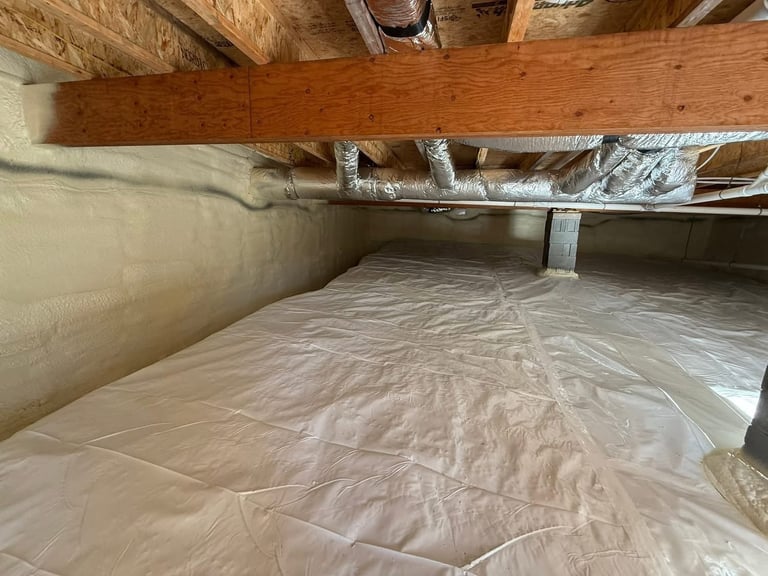 Crawl space under house with plastic vapor barrier, wooden support beams, and insulation visible on pipes