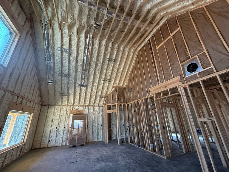 Interior of a residential home under construction showing wooden framing, exposed studs, drywall, and concrete floor